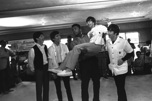 OBRÁZOK - Na tejto fotografii z 18. februára 1964 boxer Cassius Clay (Muhammad Ali) zdvihne Ringo Starr, jedného z Beatles, do vzduchu, zatiaľ čo speváci navštívili Claya
